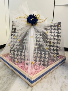 a clear box with blue and white bows on it's lid sitting on a marble countertop