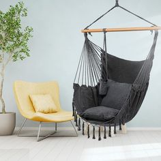 a hammock chair hanging from the ceiling next to a yellow chair