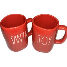 two red coffee mugs with the words santa joy written on them, sitting side by side