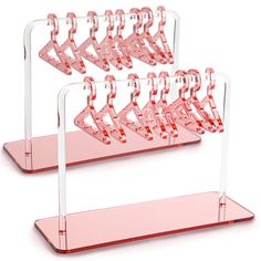 two pink acrylic racks with clear plastic hangers on each side and one holding several pairs of scissors