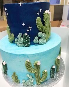 a three tiered cake decorated with green and blue frosting, cacti and stars