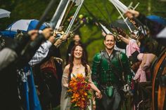 a man and woman dressed in medieval clothing walking down the street with swords on their heads