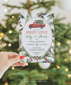 someone holding up a christmas card in front of a tree