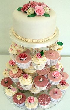 a three tiered cake with pink and white cupcakes