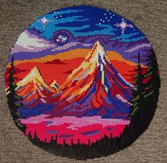 a cross stitched picture of a mountain with stars in the sky and trees on it