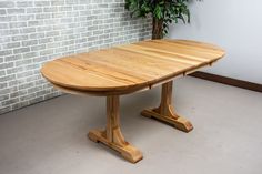 a wooden table sitting in front of a brick wall next to a potted plant