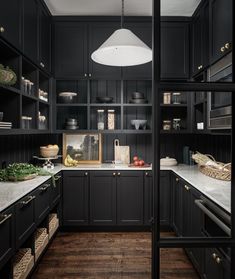 a kitchen with black cabinets and white counter tops is pictured in this image, the light fixture hangs over the sink