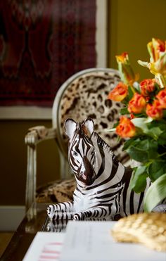 a zebra figurine sitting on top of a table next to a vase filled with flowers