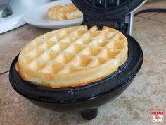 a waffle maker sitting on top of a counter next to some plates with food