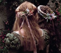 two women with long hair and flower crowns on their heads are standing in front of flowers