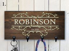 the personalized family name sign is hanging on a wall with two keys in it