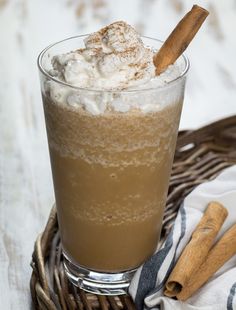 a glass filled with ice cream sitting on top of a table next to cinnamon sticks