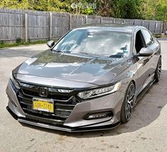 a gray car parked in front of a wooden fence