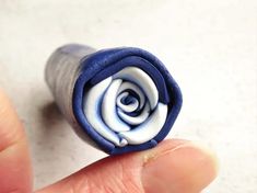 a small blue and white rose shaped object in someone's hand, on a table