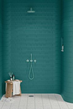 a bathroom with green walls and tile flooring, including a shower head in the corner