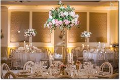 a tall gold vase filled with pink and white flowers on top of a dining room table