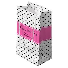 a white and black polka dot gift bag with a pink ribbon on the front that says happy birthday & congratulations