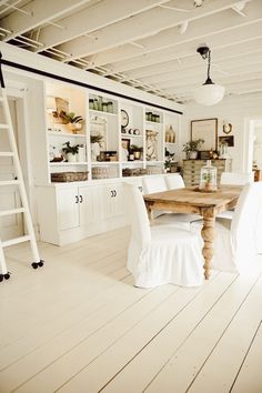 a dining room with white chairs and a wooden table in the middle of the room