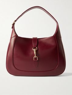 Gucci's small 'Jackie' bag takes its curved silhouette from the original style that debuted in the '60s and even boasts the same gold-tone piston clasp. Crafted in Italy from burgundy leather, it's suspended on a thick strap that can be adjusted to your perfect drop. It has plenty of space inside for everyday essentials, like your wallet, keys, cell and compact. Classic Gucci Bags With Gold-tone Hardware, Classic Gucci Shoulder Bag With Gold-tone Hardware, Gucci Bags With Metal Hardware For Work, Classic Gucci Shoulder Bag For Everyday Luxury, Gucci Bags With Gold-tone Hardware For Formal Occasions, Formal Gucci Bag With Gold-tone Hardware, Classic Shoulder Bag With Horsebit Detail, Luxury Gucci Bag With Brass Hardware, Elegant Gucci Bag With Horsebit Detail