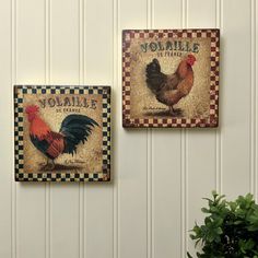 two roosters are hanging on the wall next to a potted plant