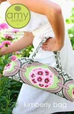 a woman carrying a green and pink flowered purse in front of some purple flowers