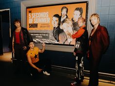 three men are posing in front of a poster for the 5 seconds of summer show