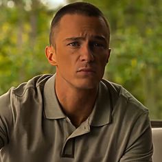 a man sitting in front of a window wearing a polo shirt