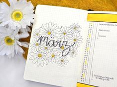 a notebook with the word mom written on it next to some daisies and flowers