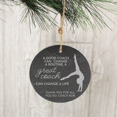 a black ornament hanging from a pine tree with an inspirational quote on it