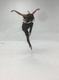 a person jumping in the air on a snow covered ground with their arms outstretched and legs spread out