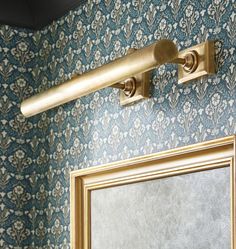 a bathroom mirror sitting next to a wall with a gold framed mirror on it's side