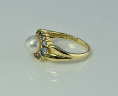 "14K Yellow Gold Pearl and Tanzanite ring, 6.5mm white pearl center, tanzanite halo, 12 stones, .5\" across ring, Ring size 7, Circa 1990, 3.9 grams Stock # BB234R23 Most rings are sizable for a small fee. If the ring you are considering is the incorrect size contact us for a quote. This listing contains photographs of the actual item you will receive. Our items are in excellent condition with little or no signs of wear and many are one of a kind pre-owned estate finds. Please look closely at th Formal Multi-stone Pearl Ring In Fine Jewelry Style, Classic Multi-stone Pearl Ring For Formal Occasions, Gold Coin Ring, 12 Stones, Tanzanite Ring, Coin Ring, New Bands, White Band, Fine Jewelry Designers