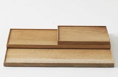 three wooden trays sitting side by side on a white surface with one empty and the other closed