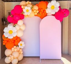 an arch with balloons and flowers on it