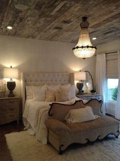 a large bed sitting under a chandelier next to a white rug on top of a wooden floor