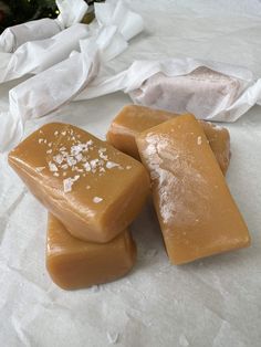 three pieces of caramel colored soap sitting on top of white paper next to a christmas tree