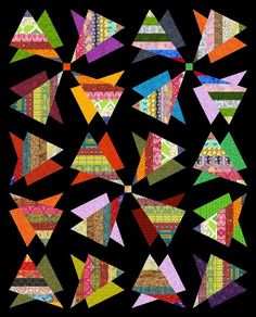 an abstract quilt made with different colors and shapes on a black background, including triangles