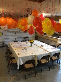 a long table with many balloons hanging from the ceiling