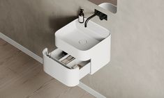 a white sink sitting on top of a wooden floor next to a wall mounted faucet