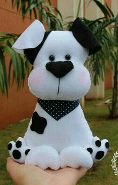 a hand holding a white stuffed dog with black spots