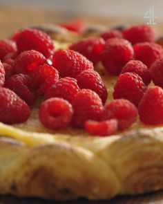 a pie with raspberries on top sitting on a table