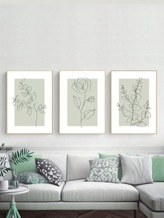 three framed art prints hanging on the wall above a white couch in a living room