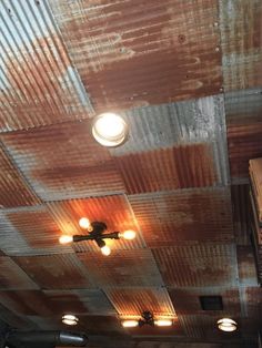 an old tin ceiling with some lights on it and rusted metal covering the ceiling