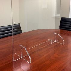 an empty conference table with black chairs and a clear acrylic sign on the wall