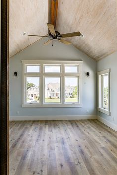 an empty room with three windows and a ceiling fan in the middle of the room