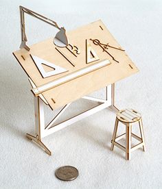 a miniature desk and stool are on the floor next to a quarter dollar bank note