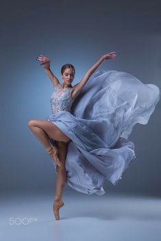 a woman in a blue dress is dancing with her legs spread out and arms outstretched