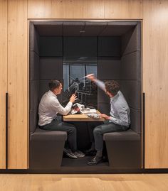 two men sitting at a table in a room