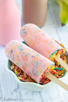 two popsicles with cereal and sprinkles in a bowl