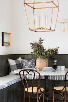 a dining room table with two chairs and a potted plant